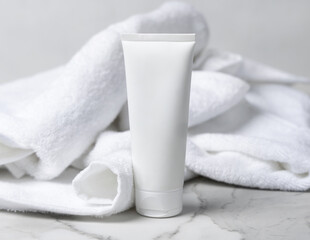 Mockup of white blank squeeze cosmetic tube near white bath terry towel. Spa hotel context