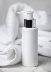 Mockup of white blank pump cosmetic bottle near white bath terry towel in hotel bathroom