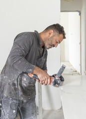 Craftman in grey shirt cuts a gray marble tile using an angle grinder. Handy men at work, hands closeup