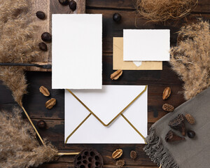 Cards and envelopes boho mockup on dark wood near natural decor and pampas grass top view
