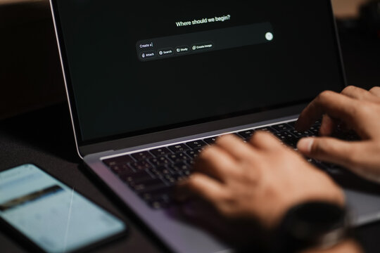 The hands of a man using a laptop or smartphone to operate artificial intelligence (AI), inputting commands and interacting with AI, AI assistants, chatbots, chat GPT.