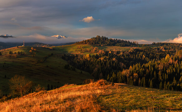 Osturna, Slovakia - Panoramic view on High Tatras mountains National Park on a sunny autumn morning with warm golden sunrise colors on foliage, radio tower and foggy mountains at background