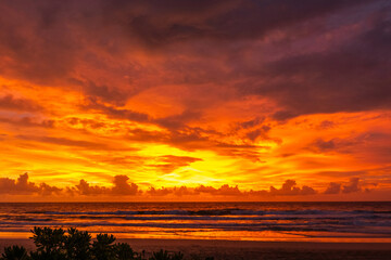 Stunning orange sunset sky over calm ocean waves with golden light reflections. Ideal for travel themes, tropical landscapes, peaceful backgrounds, meditation, or beach resort branding.