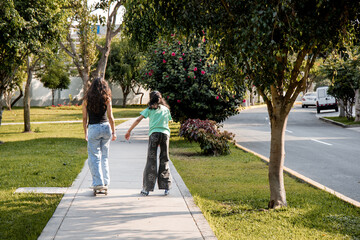 Rear View of Two Friends Skating on Quads and Rollerblades Holding Hands