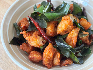 Close-up of traditional Thai deep-fried chicken bites: golden‑brown, crispy pieces of seasoned chicken mixed with glossy fried kaffir lime leaves