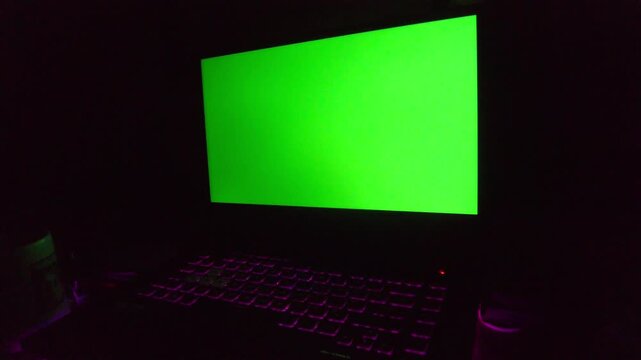 High-quality laptop green screen mockup with a bright chroma key display and blue backlit keys. Ideal for 2026 tech demos, software previews, and cinematic visual effects in a dark, modern environment