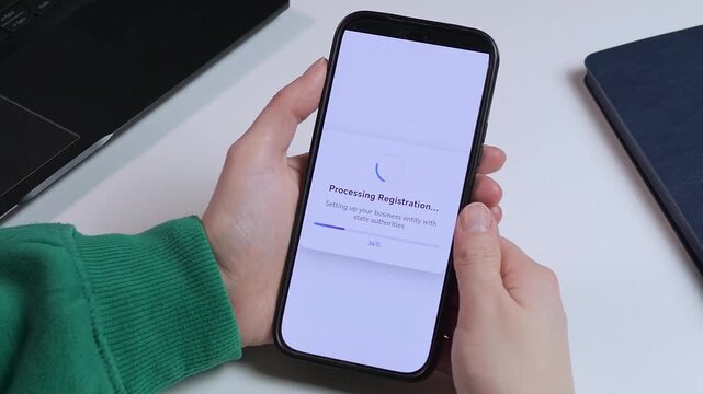 Hands holding a phone during a quick LLC registration. Video shows a 100 percent compliance guarantee and a final success message. Great for marketing, financial services, and videos about young