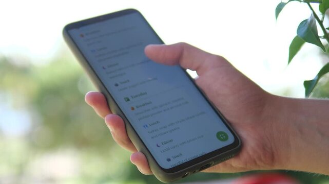 Browsing a digital healthy meal guide on mobile. User selects nutritious recipes for the week. Great for nutrition blogs, diet programs, and personal wellness storytelling. Trendy healthcare tech