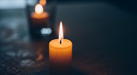 Two lit candles on dark surface.