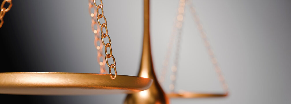 The gleaming golden balance scale, a symbol of justice and legal proceedings, is captured in a detailed close-up shot