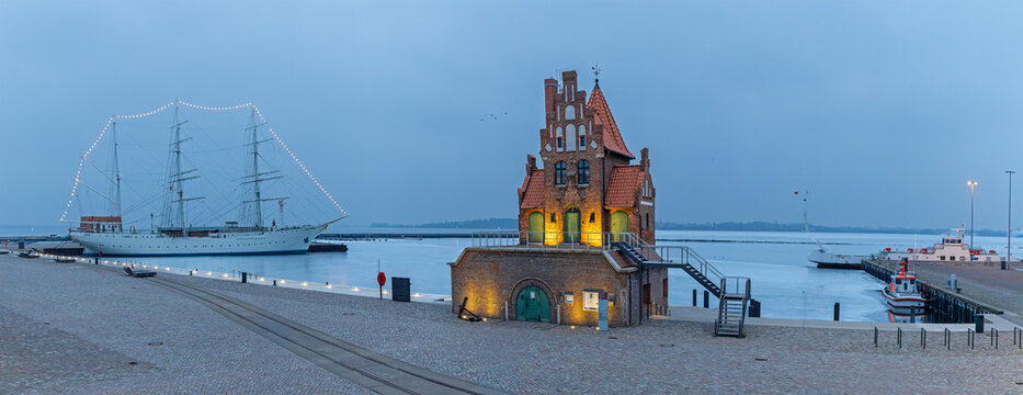 Panoramic view of Stralsund harbor with historic pilot house and sailing ship Gorch Fock at early winter morning