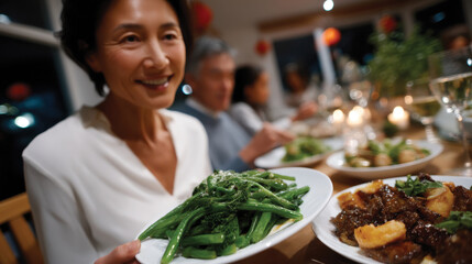 Naklejka premium A delighted woman presents a fresh serving of green beans at dinner, radiating joy and enthusiasm while gathered around a warm table with family enjoying the meal.