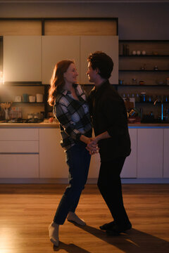Couple dancing in a warm kitchen at home, smiling and enjoying a cozy evening together