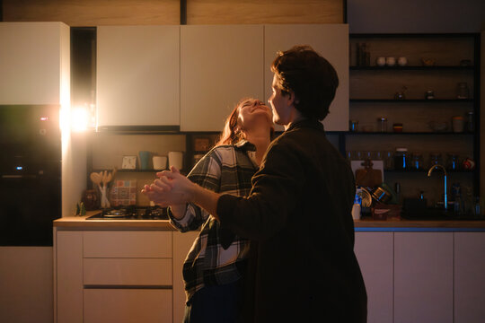 Couple dancing in a cozy kitchen at night with warm lighting and smiles