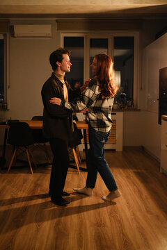 Couple dancing in a cozy kitchen at night, warm lighting, connection and joy in a home
