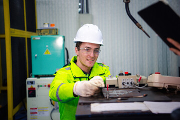 Robotic machine engineers is checking the operation of a robot arm manufacturing machine and welding robots in a production process at an industrial factory.