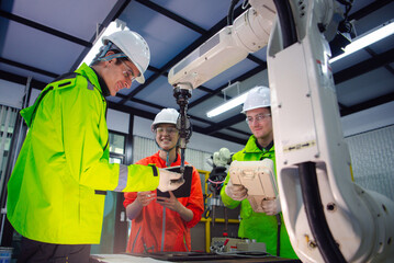A team of robotic machine engineers is checking the operation of a robot arm manufacturing machine and welding robots in a production process at an industrial factory.