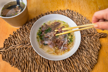 Soup Pho Bocelestine noodles, mixed with chopsticks (in motion, blurred).