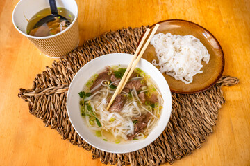 Vietname soup Pho bo with chopsticks, rice noodle on plate, bowl with soup,