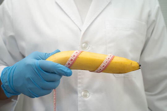 Male doctor stands holding a banana, penis health.