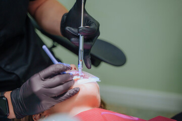 The dentist administers anesthesia to the patient. Dental treatment in a private medical clinic. The patient is injected with the drug from a syringe into the gum.