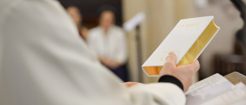 Un pr&ecirc;tre tient le livre de la Bible ferm&eacute; dans la main, lors d'une c&eacute;r&eacute;monie dans une &eacute;glise, format banni&egrave;re