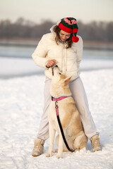 A woman hugs an Akita dog in a snowy landscape, both smiling and enjoying the moment