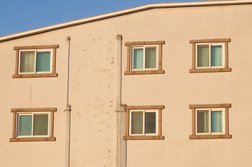 Obraz premium Sunlit Residential Building Facade With Repeating Windows