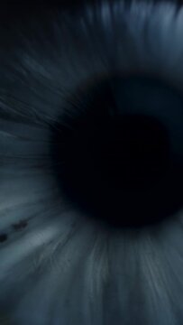 Vertical video: Zooming camera capturing single human eye close in tight crop, showing iris fibers