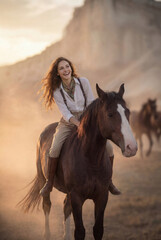 Obraz premium A young woman with a brown horse in a scenic valley with mountains background