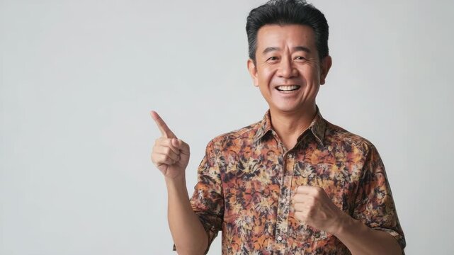 A smiling man in a patterned shirt confidently pointing upward, suggesting success or agreement.