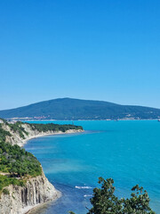 Obraz premium Scenic cliff coastline with turquoise sea and distant green hills