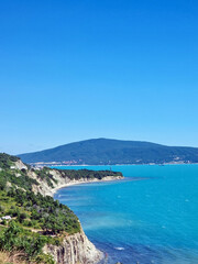 Fototapeta premium Scenic cliff coastline with turquoise sea and distant green hills