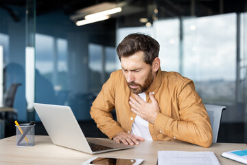 Fototapeta premium Businessman manager feeling sudden discomfort and pain in his chest while working on laptop at desk, dealing with symptoms of potential heart attack or stress-related illness