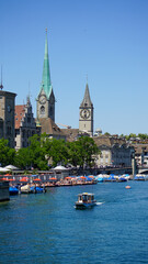 A scenic view of a historic European city with a church steeple and clock tower along a waterfront