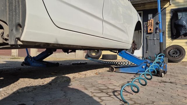 Tire service. A car lifted with a jack for seasonal tire changes