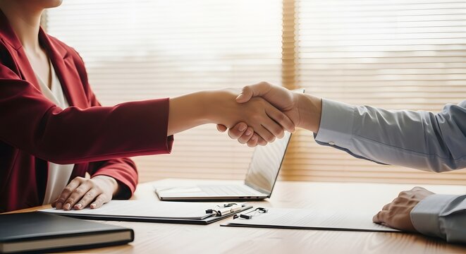 Two people shaking hands in an office.