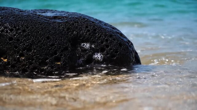 Macro Video Of Turquoise Wave Washing Over Volcanic Rock On Tropical Beach.