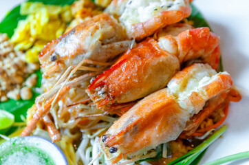Prawn Pad Thai, close-up. Pad Thai with grilled river prawns, stir fried noodles in rich sauce served with fresh vegetables. Authentic Thai cuisine, ideal for food, restaurant, and travel content