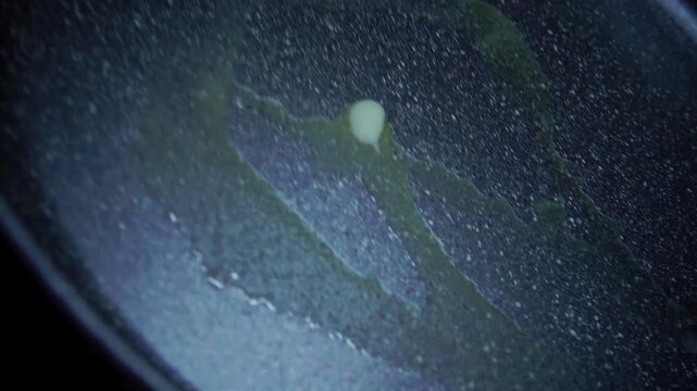 Close up of butter sliding and melting on hot non-stick pan surface while making breakfast