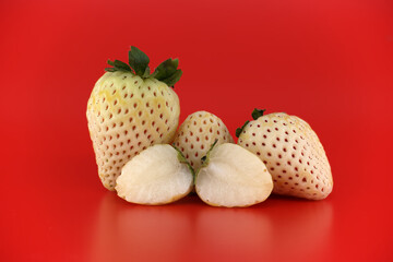 Unique white pineberries with red seeds displayed on a vibrant red background