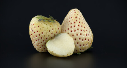 Unique white pineberries with red seeds displayed against a dark background