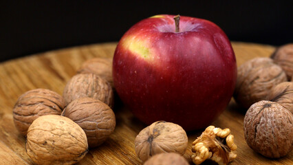 Red apple and walnuts on rustic wooden surface.