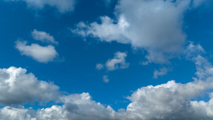 Obraz premium Wide-angle view of a vibrant blue sky filled with scattered white and grey cumulus clouds of various sizes, capturing a bright and clear day.