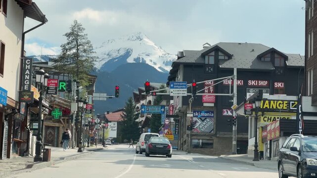 Pov drive on Pirin street in ski resort city of Bansko, Bulgaria with view of mountain ski slopes at background