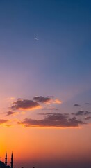Obraz premium Sunset over the Mosque silhouetted minaret, moon, warm colors, soft light, vertical, peaceful, religious architecture, evening, beautiful sky.
