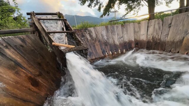 Water flow trough with a vintage wooden swirl washing machine and a wooden handle