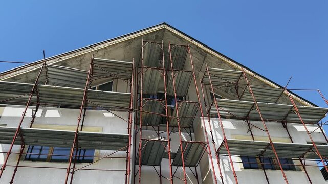 Home renovation, reconstruction house, scaffolding walls. External walls in houses, energy saving wall insulation for houses, outside renovation, and old building facade reconstruction.
