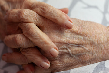 Hands of a senior female fingers crossed