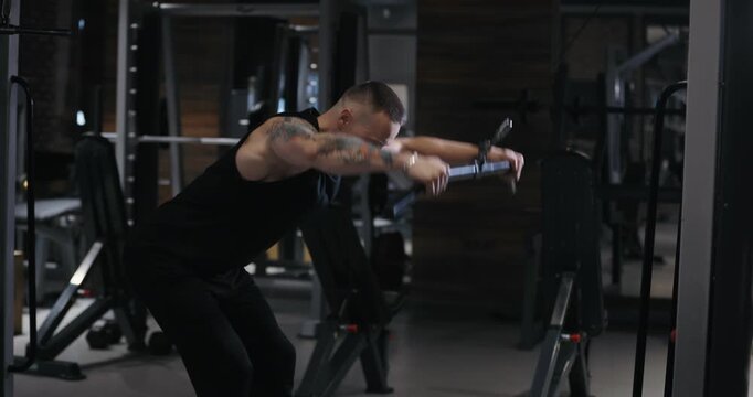 A man doing pullover exercise on training apparatus pumping his muscles in the gym